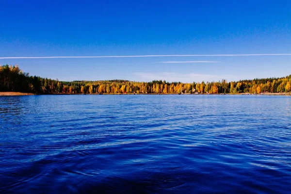 Ősz lombja, ősz színes erdei kék tóval, piros kabinnal Finnországban. — Stock Fotó
