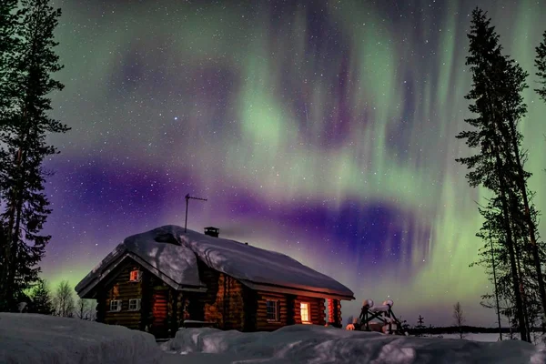 Polar arctic Northern lights Aurora Borealis activity over wooden hoseu in winter Finland, Lapland — Stock Photo, Image