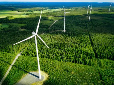Finlandiya'da yaz ormanında yel değirmenleri havadan görünümü. Temiz ve Yenilenebilir Enerji ile elektrik enerjisi için rüzgar türbinleri 