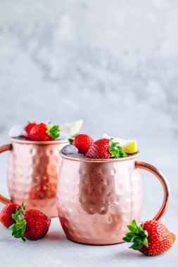 Çilek ve limon ile bakır kupalarda ferahlatıcı buzlu Moskova katır alkollü kokteyl 