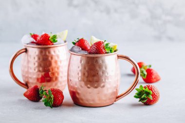 Çilek ve limon ile bakır kupalarda ferahlatıcı buzlu Moskova katır alkollü kokteyl 