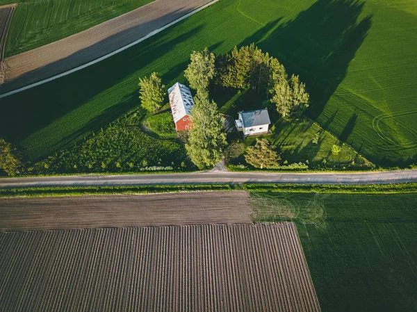 Εναέρια θέα της γης με κόκκινο αχυρώνα και τα σπίτια και τη συγκομιδή χωράφι στη Φινλανδία — Φωτογραφία Αρχείου