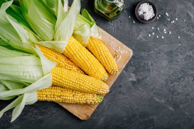 Koyu gri taş arka plan koçan üzerinde taze tatlı altın mısır