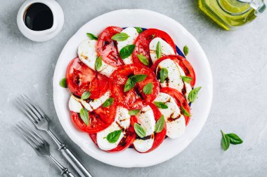 Domates, fesleğen, balzamik sirke ve zeytinyağı ile mozzarella Caprese salatası. 