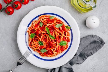 Gri taş arka plan üzerinde domates soslu İtalyan spagetti makarna, fesleğen ve parmesan peyniri. Yukarıdan görüntüle.