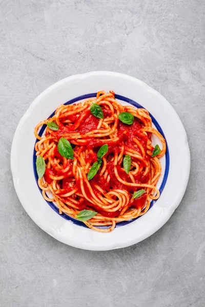 Pasta italiana de espagueti con salsa de tomate, albahaca y queso parmesano sobre fondo de piedra gris. Vista desde arriba . — Foto de Stock