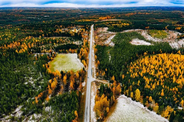 Vista aérea da primeira floresta colorida de outono de neve e uma estrada com carro na Finlândia . — Fotografia de Stock