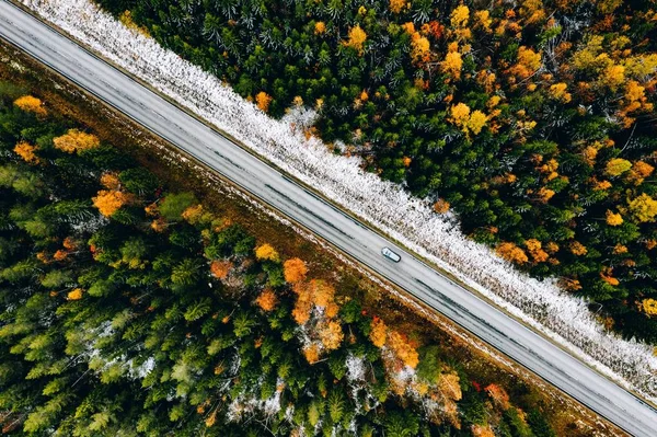 フィンランドで最初の雪の秋の色の森と車で道路の空中ビュー. — ストック写真