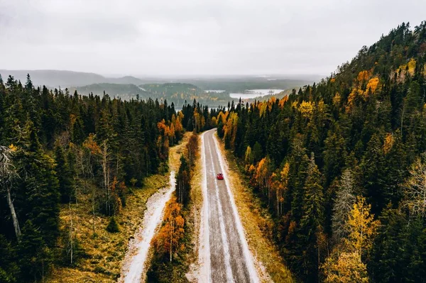 Vista aérea del primer bosque nevado de color otoñal en las montañas y una carretera con coche en Finlandia Laponia . —  Fotos de Stock