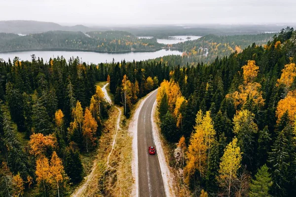 Vista aérea del primer bosque nevado de color otoñal en las montañas y una carretera con coche en Finlandia Laponia . —  Fotos de Stock