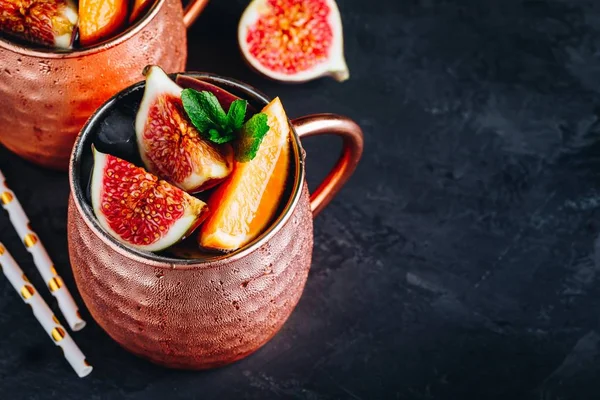 Инжир москва мул холодный коктейль в медной чашке с апельсинами и мятой — стоковое фото