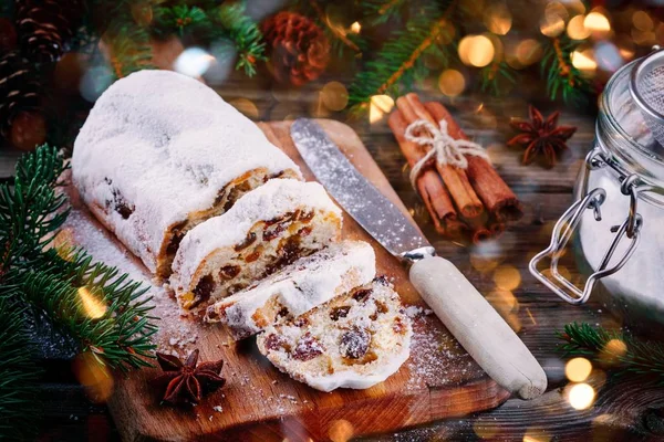 Tradycyjne ciasto owocowe Christmas Stollen na drewnianym tle z lampkami świątecznymi — Zdjęcie stockowe