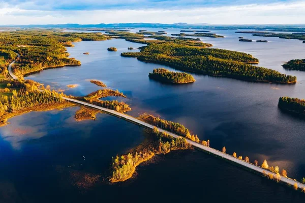 Letecký pohled na silniční most přes modrá jezera s ostrovy a barevný podzimní les ve Finsku. — Stock fotografie