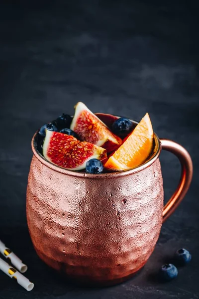 Инжир москва мул холодный коктейль в медной чашке с черникой и апельсином — стоковое фото