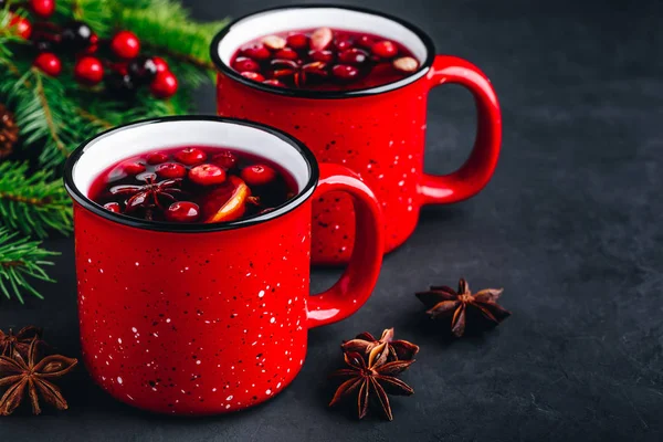 Traditional Christmas Mulled Wine drink with cranberries, orange slices and spices in red mugs — Stock Photo, Image
