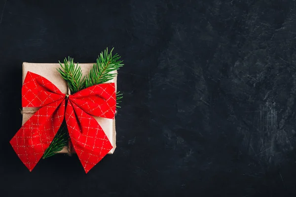 Confezione regalo di Natale. Scatola regalo di Natale con fiocco rosso e ramo d'albero su sfondo di pietra scura . — Foto Stock