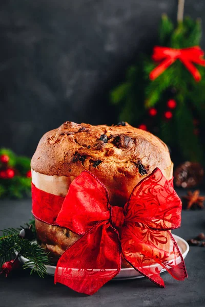 Традиционный рождественский торт из панеттоне с сухофруктами, украшенный красной лентой — стоковое фото