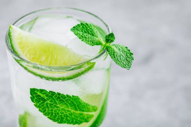 Buzlu mojito kokteyli, gri taşlı arka planda taze nane ve limon. Soğuk yaz içeceğini tazeliyorum..
