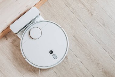 Kablosuz robot elektrik süpürgesi, temiz ahşap zemindeki şarja geri döndü. Akıllı ev teknolojileri.