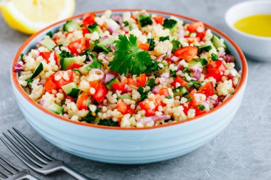 Taze domatesli kuskus tabbouleh salatası, salatalık ve gri taştan arka planda kırmızı soğan.
