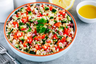 Taze domatesli kuskus tabbouleh salatası, salatalık ve gri taştan arka planda kırmızı soğan.