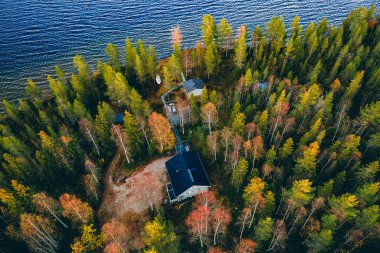 Sonbahar renklerinde ahşap kulübe manzarası Kırsal sonbaharda mavi göl ormanı, Finlandiya