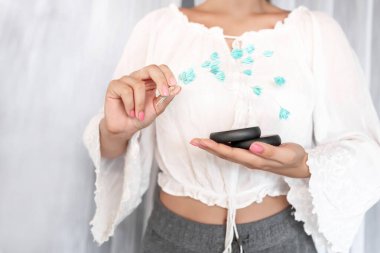 Yakın plan: güzel pembe manikürlü beyaz bluzlu bir bayan spa tedavisi ve mavi çiçekler için iki siyah taş tutuyor. Spa ve cilt bakımı, masaj..