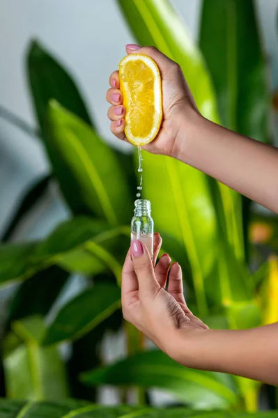 一只雌性手将柠檬汁挤压入玻璃瓶 天然化妆品的概念 — 图库照片