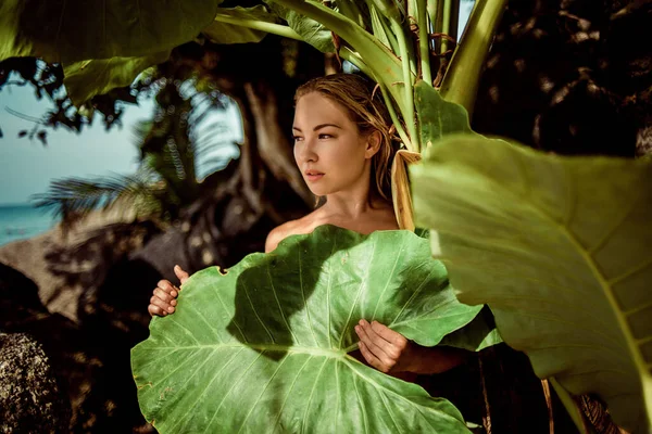 Un beau visage. Modèle femme avec maquillage naturel et peau saine avec des plantes à feuilles vertes. — Photo