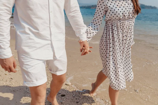 El amor - la pareja romántica en la ropa blanca tomados de la mano en la playa al atardecer . — Foto de Stock