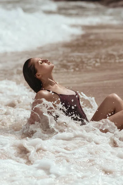 Mladá opálená kráska se koupe v mořských vlnách a zavírá oči. — Stock fotografie