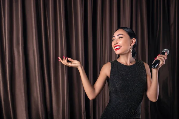 Dama feliz, dama en un hermoso vestido de noche, posando con un micrófono en la mano — Foto de Stock