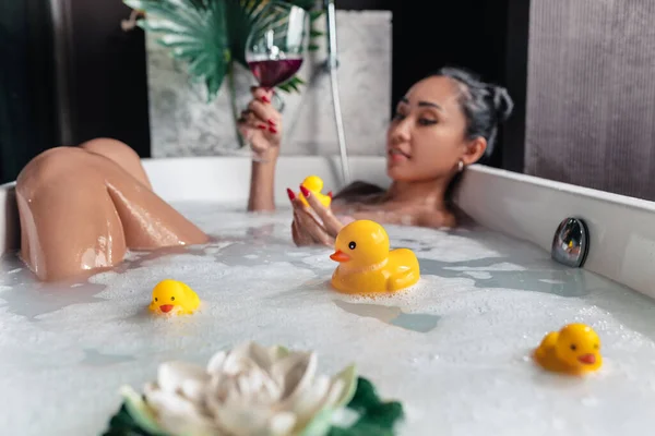 Menina posando enquanto deitado em um banho de espuma — Fotografia de Stock