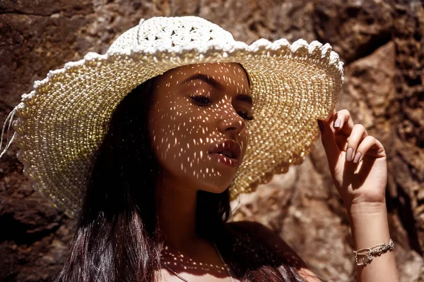 Portrait de mode en gros plan : une fille avec un chapeau de paille et des ombres sur le visage détend les yeux fermés — Photo