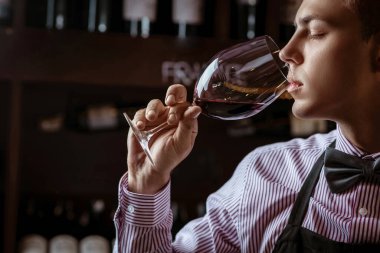 Profesyonel bir şarap garsonu yeteneğini yeni açılmış bir şarap şişesinin mantarını koklayarak gösterir. Sommelier..