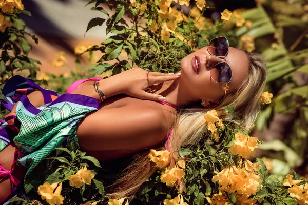 Die lächelnde braungebrannte Blondine im schicken blauen Badeanzug mit Strass ruht sich auf dem Sommerurlaub aus — Stockfoto