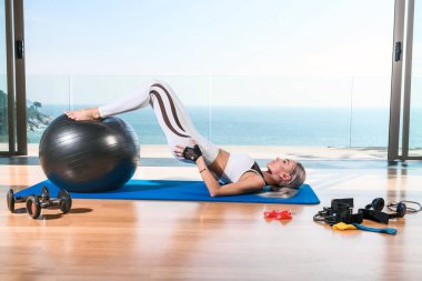 Çekici sarışın pencerenin önünde egzersiz yapıyor.