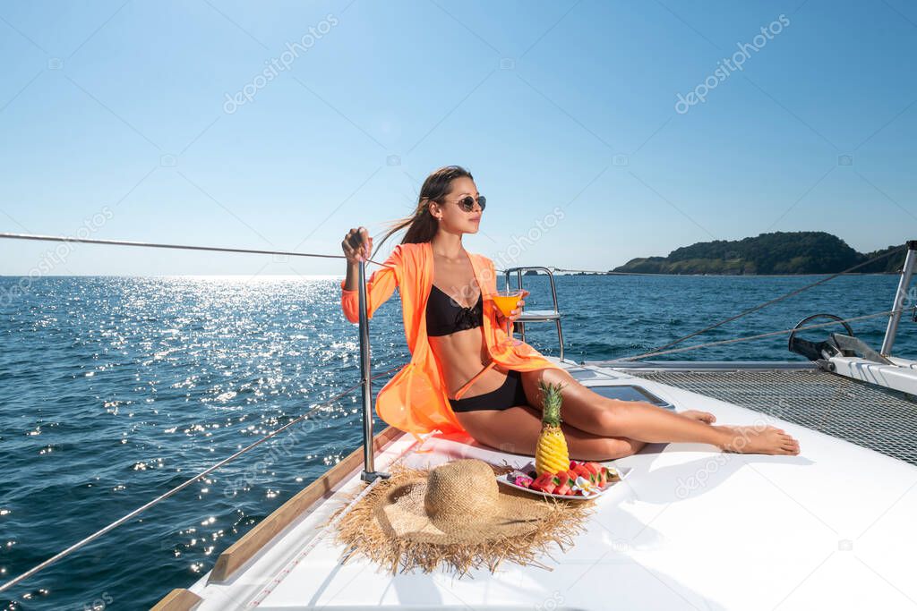 Young beautiful girl on the bow of the yacht