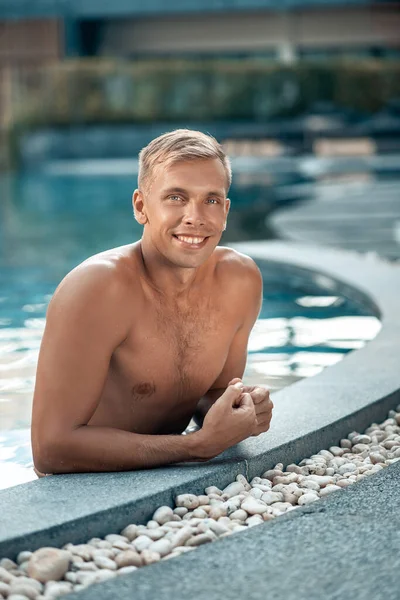Havuzda poz veren yakışıklı sarışın genç bir adam. Yaz tatili. Tatiller ve seyahat kavramı
