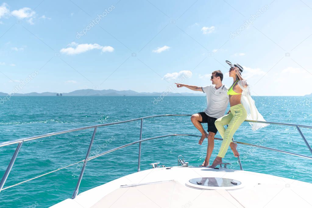 Beautiful couple in love on the edge of a yacht. A man shows a route with his hand. Travel and boat trips concept