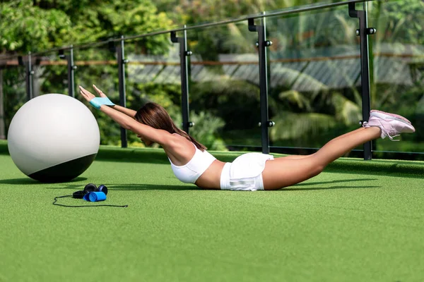 Uma Menina Delgada Realiza Exercício Alongamento Deitada Gramado Verde Terraço — Fotografia de Stock