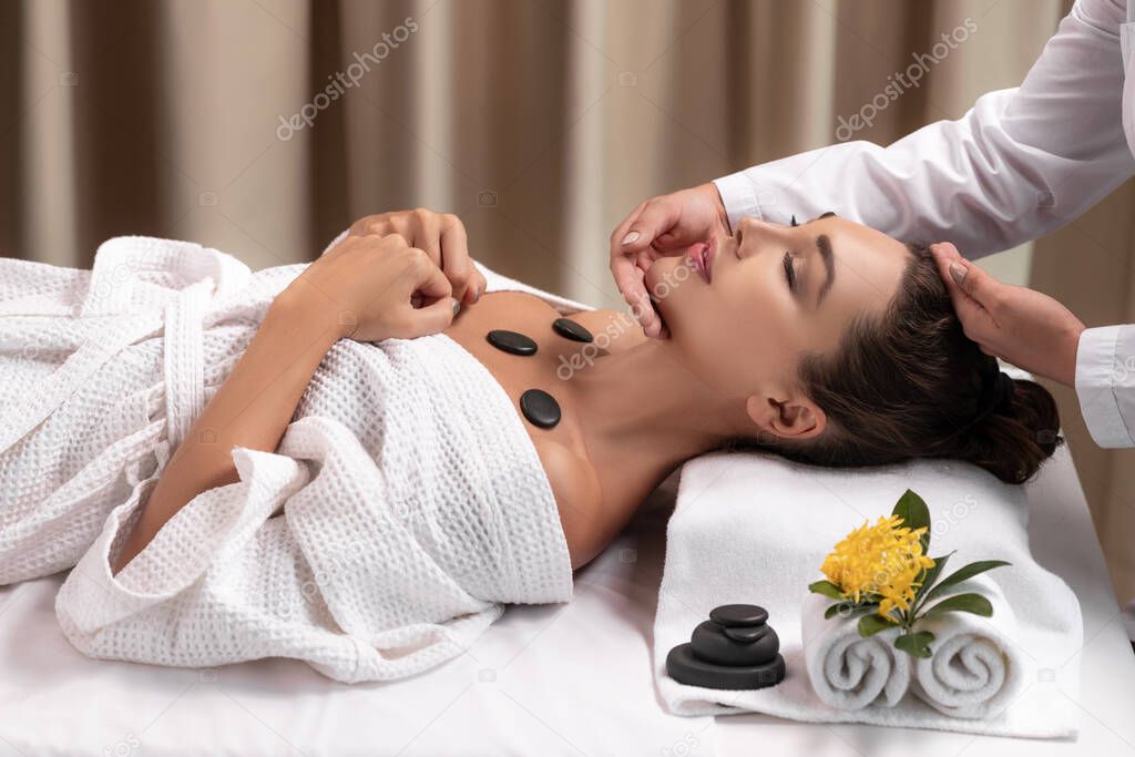 Beautiful young woman receiving face massage in spa salon