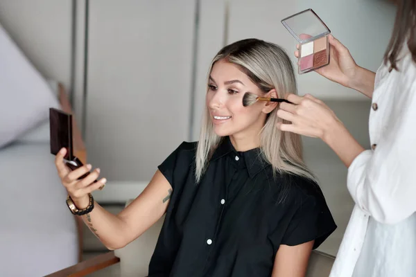 smiling young woman in makeup room doing her makeup