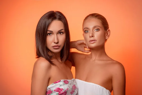 Porträtt Två Attraktiva Kaukasiska Kvinnor Blond Och Brunett Isolerad Orange — Stockfoto