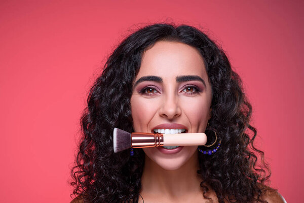 Portrait of a makeup artist. Make-up courses. The concept of self-expression of master classes. Woman holding makeup brushes in her mouth