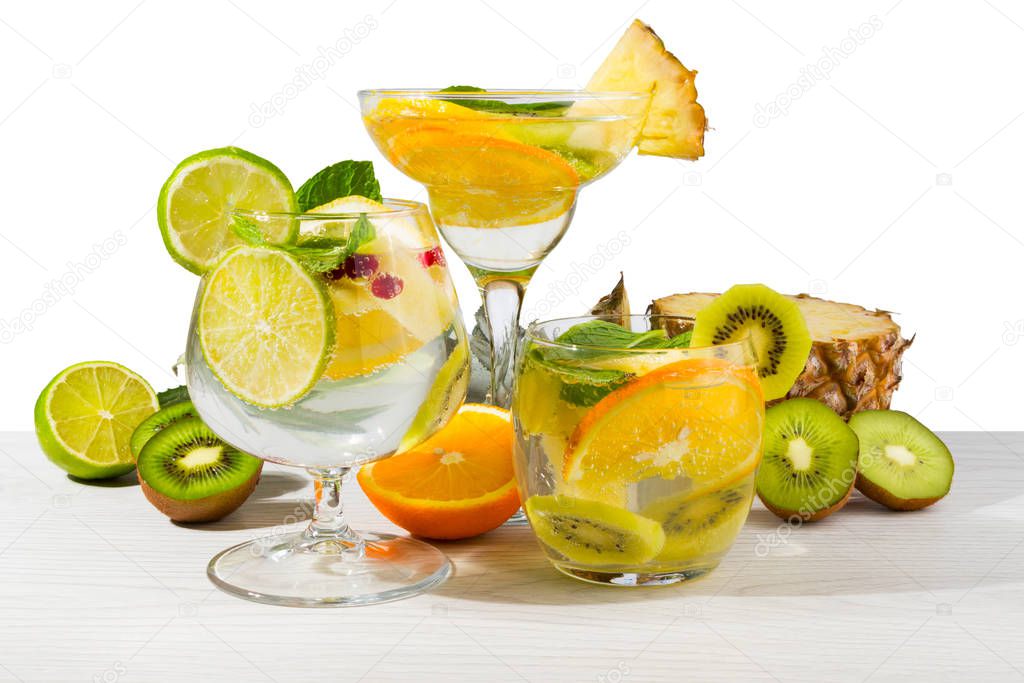 Three different cocktails with fruit on a light wooden table. White isolated