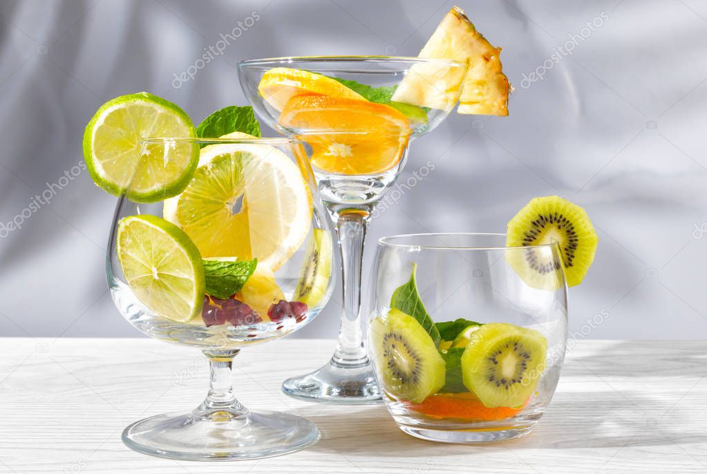 Three glasses for cocktails with fruit and berries without liquid