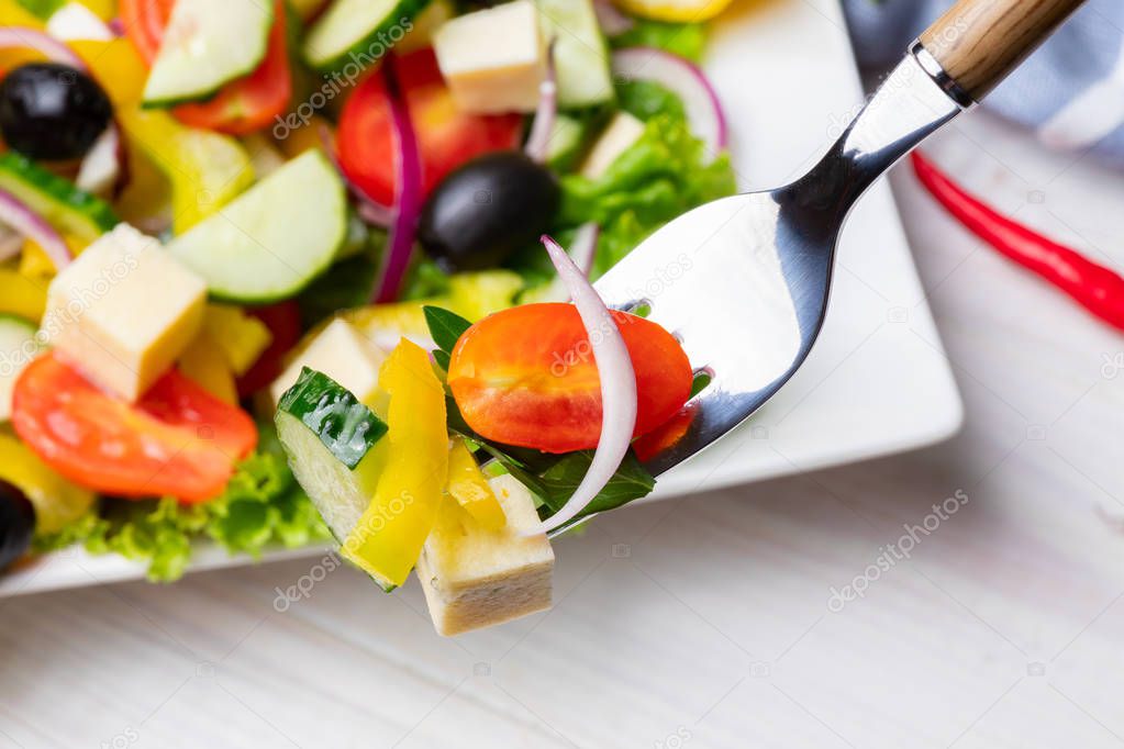 Light summer vegetable salad on a fork. Close-up, top view.