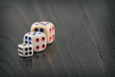 koyu bulanık arka plan üzerinde farklı boyutlarda üç zar. Tonda. metin için alan