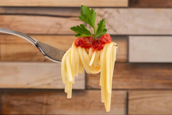 bulanık ahşap arka plan üzerinde domates sosu ve maydanoz yaprağı yakın çekim ile bir çatal üzerinde spagetti